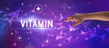 VITAMIN yazıtlarına işaret eden kırpılmış elin yakın çekimi, tıbbi konsept