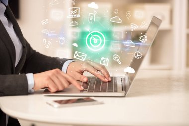 Bilgisayarda çalışan iş adamı, içinden hedef simgeler çıkıyor ve iş dünyası kavramı büyüyor.