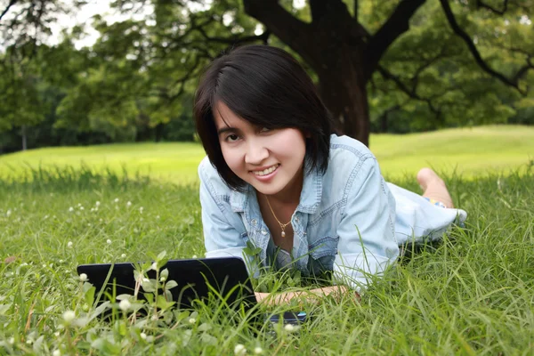 Улыбающаяся молодая девушка с ноутбуком на улице — стоковое фото