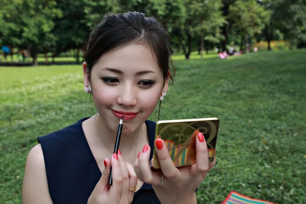 Jeune femme regarde dans le miroir et fait encre des yeux — Photo