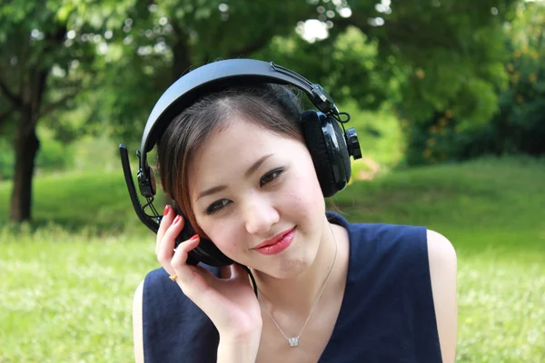 Beautiful girl listening music in the park — Stock Photo, Image