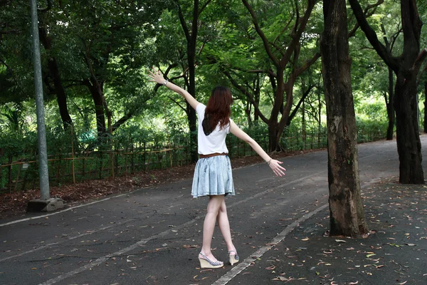 Young woman walking on path in city park — Stock Photo, Image