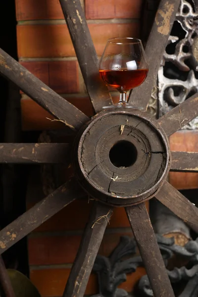 Glass of brandy on wooden wheel — Stock Photo, Image