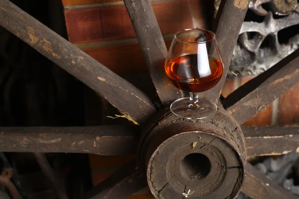 Glass of brandy on wooden wheel — Stock Photo, Image