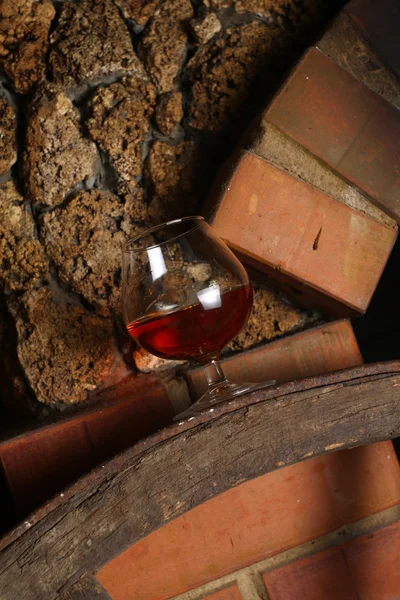 Glass of brandy on wooden wheel — Stock Photo, Image