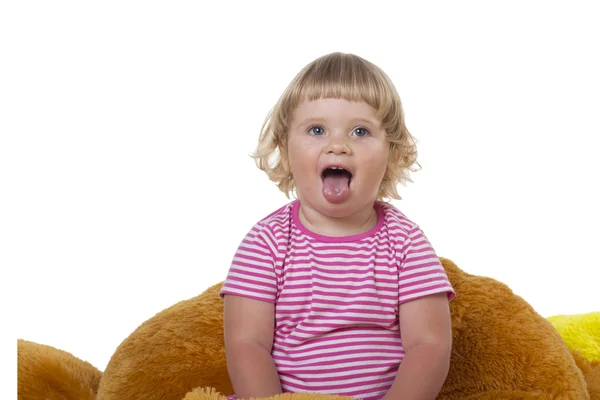 Ett barn sitter på en mjuk leksak på en vit bakgrund — Stockfoto