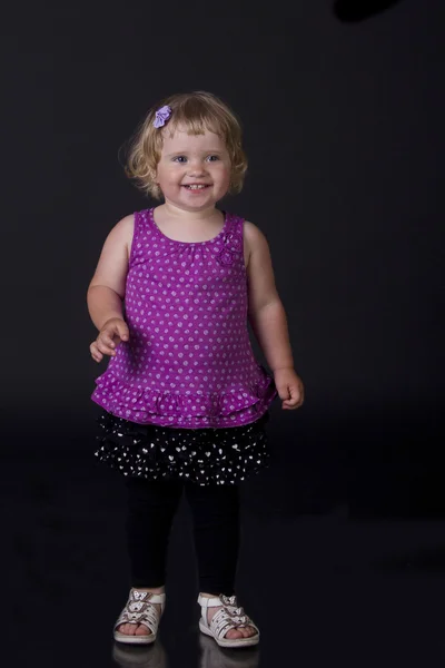 Gyönyörű mosolyt, egy kislány, egy fekete háttér — Stock Fotó