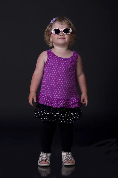 Menina com óculos de sol posando em um fundo preto — Fotografia de Stock