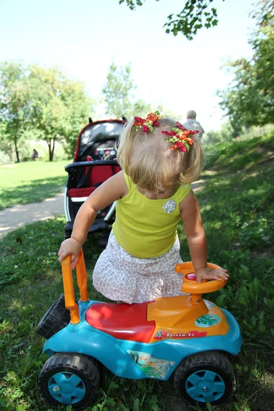 Niña conduciendo su coche de juguete en el parque, al aire libre — Foto de Stock