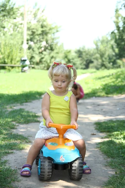 Little girl driving her toy car in the park, outdoors — Stock Photo, Image