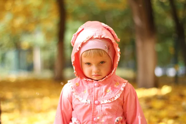 Sad little girl in autumn park — Stock Photo, Image