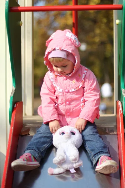 Bambina su uno scivolo parco giochi in autunno — Foto Stock