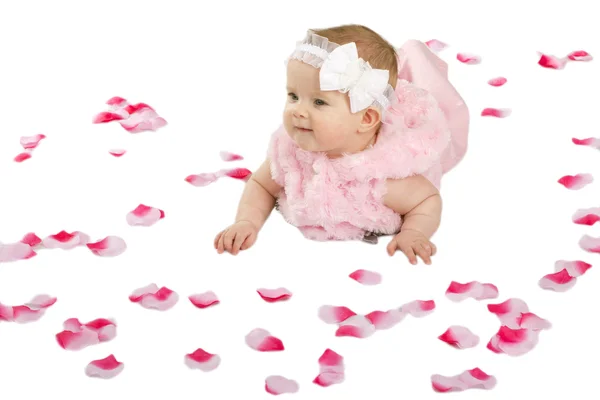 Una graziosa bambina sdraiata a terra coperta di petali di fiori — Foto Stock
