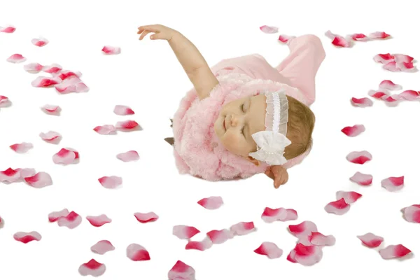 A cute baby girl lying on the ground covered in flower petals — Stock Photo, Image