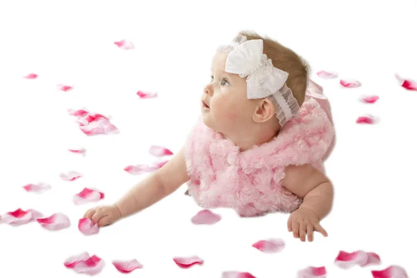 Una graziosa bambina sdraiata a terra coperta di petali di fiori — Foto Stock