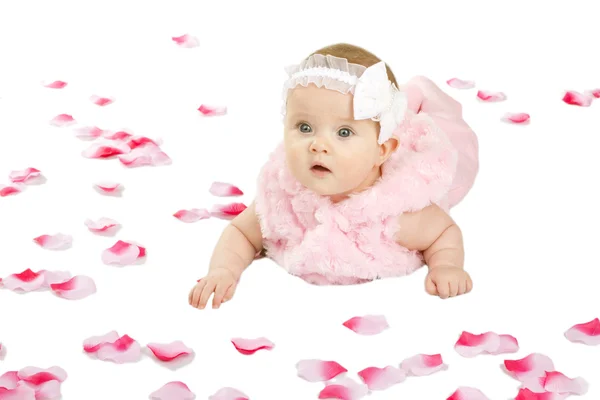 Una graziosa bambina sdraiata a terra coperta di petali di fiori — Foto Stock