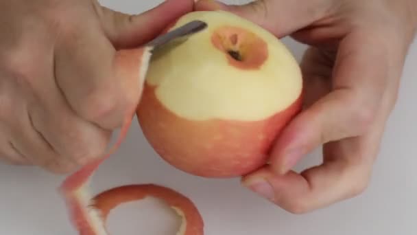 Människohänder skär peel rött äpple, metall kniv, kontinuerligt. — Stockvideo