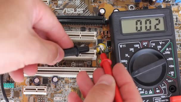 Man measures digital multimeter motherboard and processor. — Stock Video