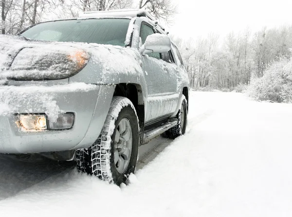 Snowy winter road behind an unrecognizable car — Stock Photo, Image