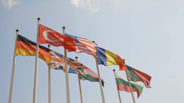 Mavi gökyüzü altındaki çeşitli ulusal bayraklar.