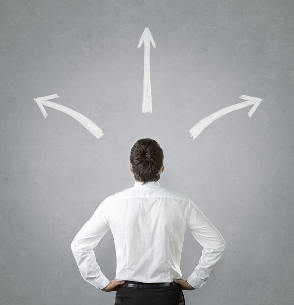 бизнесмен смотрит на нарисованные стрелы
