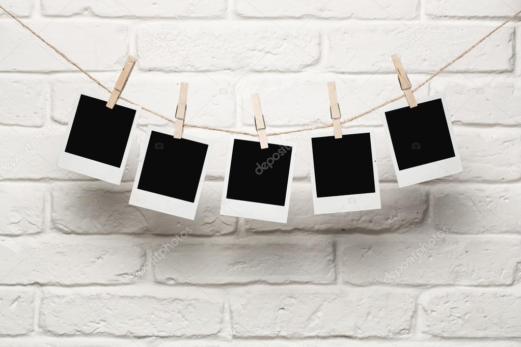 Download - Blank photos hanging on a clothesline over brick wall background...