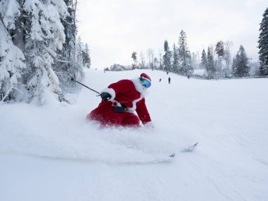 Noel Baba alp kayakçısı karlı orman kayak merkezinde yokuş aşağı kayak yapıyor.