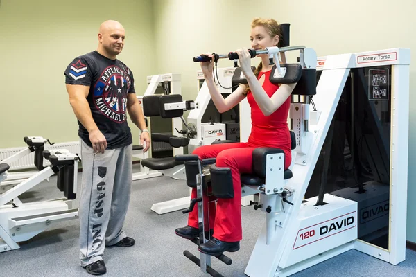 Giovane donna con un istruttore in palestra — Foto Stock