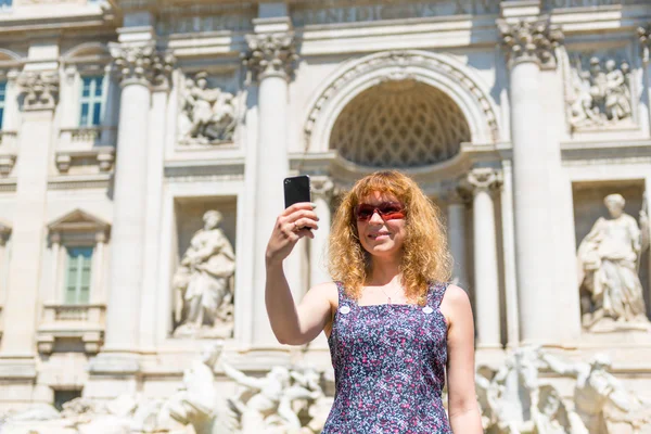 Selfie of a young female tourist on the background of the Trevi Fountain in Rome