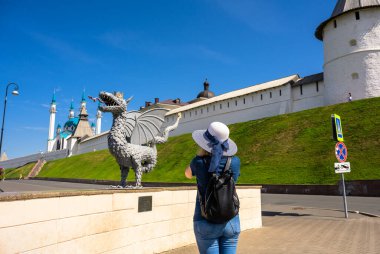 Kazan, Rusya - 16 Haziran 2021: Genç kadın Kazan Kremlin, Tataristan, Rusya 'da ejderha heykelinin fotoğrafını çekiyor. Kremlin, Kazan 'ın bir numaralı turistik ilgi odağı. Manzara, insanlar ve seyahat kavramı.