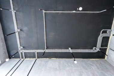 Evin tavanında elektrik kabloları ve borular var. Modern plastik hortumlar ve kablolu kanallar. Profesyonel işten sonra PVC kablo boruları hattı. Ev ya da fabrika iç dekorasyonu.