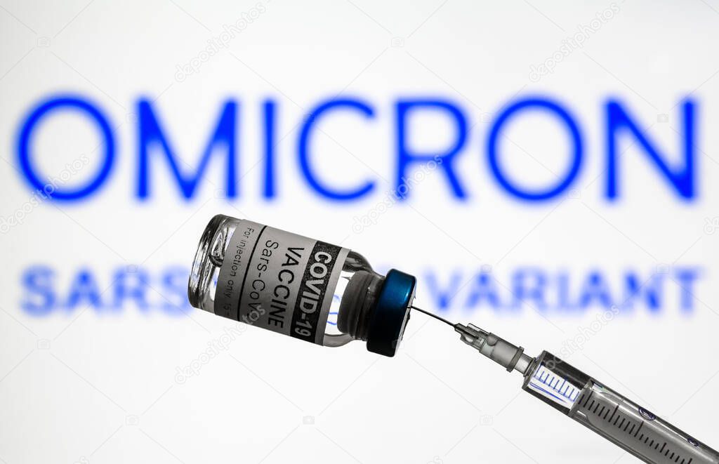 COVID-19 vaccine and syringe on background of Omicron variant info, focus on coronavirus vaccine bottle. Concept of new corona virus strains, vaccine research, healthcare, medical injection and shot.
