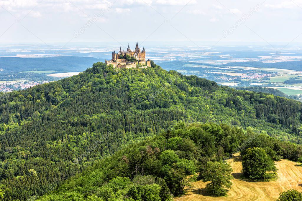 Hohenzollern Castle or Burg on mountain top, Germany, Europe. It is landmark in Stuttgart vicinity. Scenic view of German castle like palace. Landscape of Swabian Alps with field and Gothic castle.