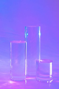 holografik neon arkaplanda üç tane cam silindir podyumu 