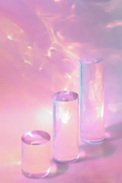 Три прозорі скляні циліндричні подіуми на пастельному рожевому фоні — стокове фото