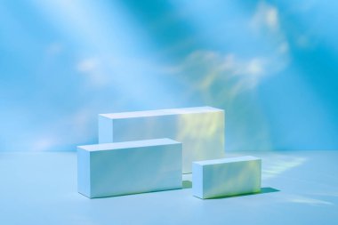 Pastel mavi neon zemin üzerinde üç dikdörtgen beyaz podyum 