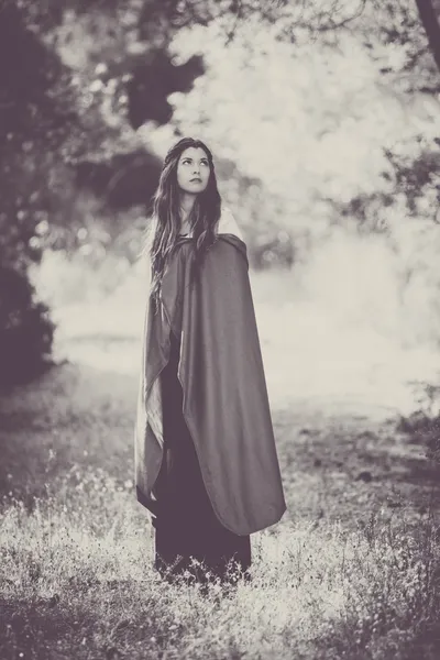 Fiction woman in cloak in forest. — Stock Photo, Image