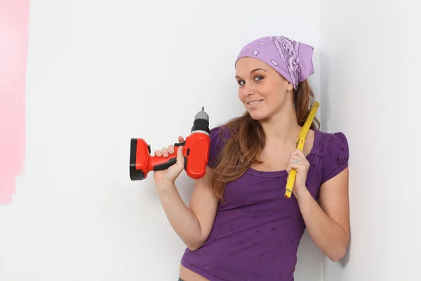 Vrouw versieren huis met draadloze elektrische boor en meetlint — Stockfoto