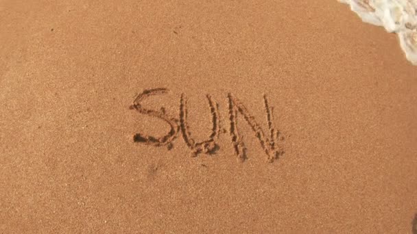 Γράμματα Του Ήλιου Στην Άμμο Ξεπλένουν Θαλασσινό Νερό Την Ηλιόλουστη — Αρχείο Βίντεο