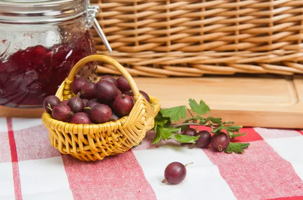 Basket with berries of a red gooseberry and jam — Stock Photo, Image