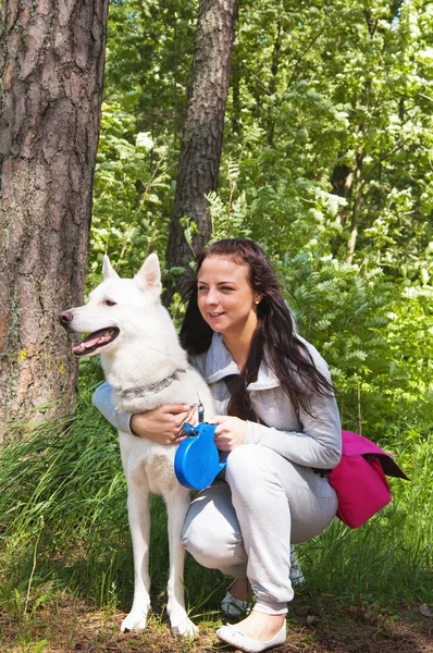 Die junge Frau mit einem weißen Hund in der Natur — Stockfoto
