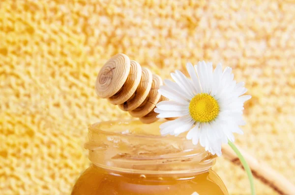 Банка мёда на фоне сотовых сот — стоковое фото