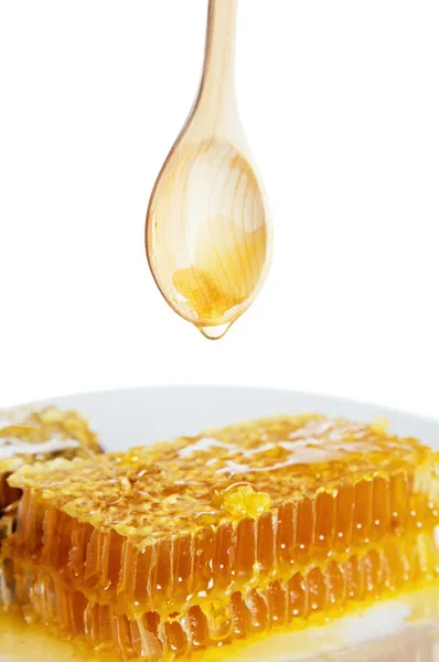 Colher com favo de mel na placa branca — Fotografia de Stock