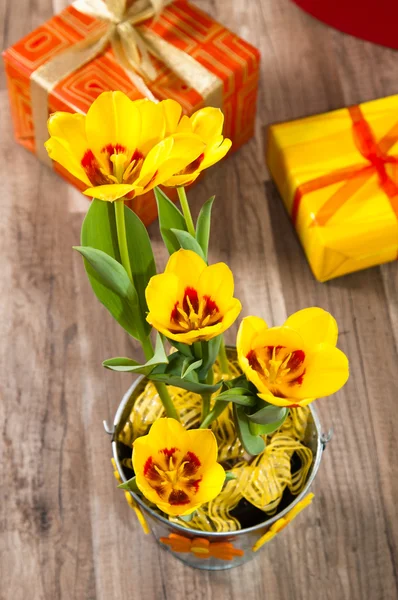 É tulipas amarelas vermelhas e caixas de presente, um close-up — Fotografia de Stock