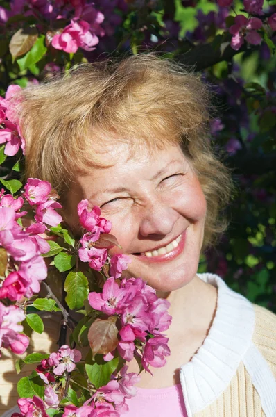 Una mujer de mediana edad en una floreciente magnolias — Foto de Stock