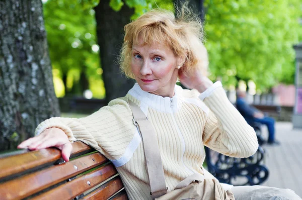 A middle-aged woman sits on a park bench — Stock Photo, Image