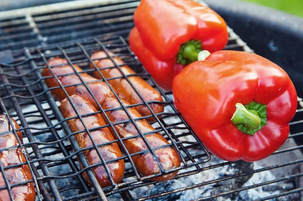 Rode paprika en worstjes op een grill, close-up — Stockfoto