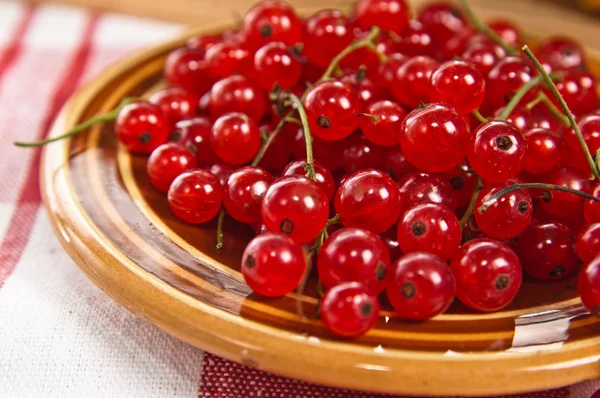 Berries of a red currant in a plate on a table — Stock Photo, Image