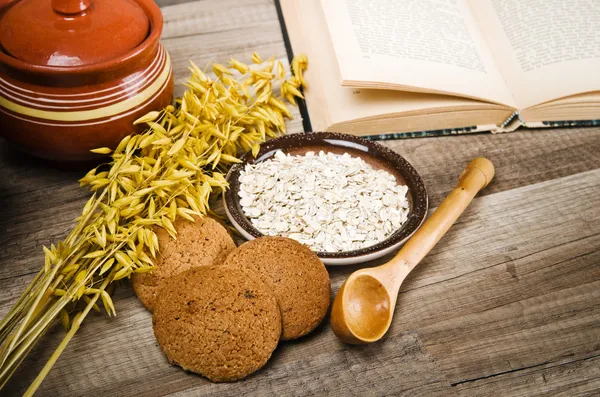 Yulaflı kurabiyeler, açık bir kitap, yemek tarifleri ve mutfak aletleri
