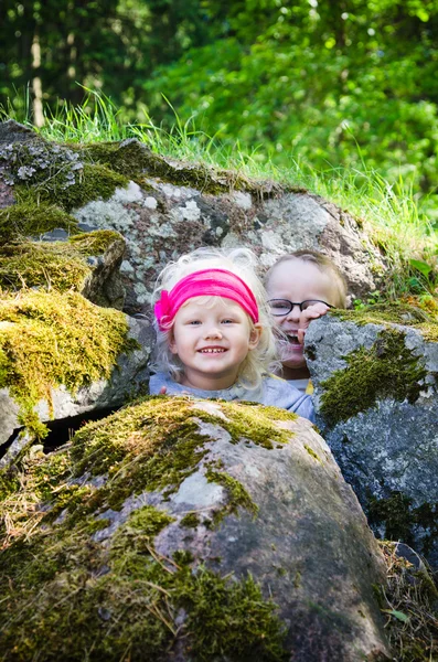 Unge barn, gutten med jenta gjemte seg blant steinene – stockfoto